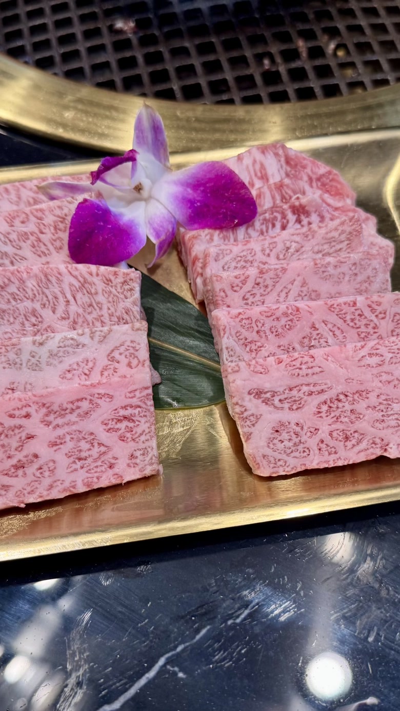 Japanese A5 wagyu short rib on a gold tray, tabletop grill at the edge of the table.